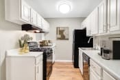 Thumbnail 4 of 16 - Affinitee at Stone Mountain Apartments photo of an open kitchen with white cabinets and a black refrigerator